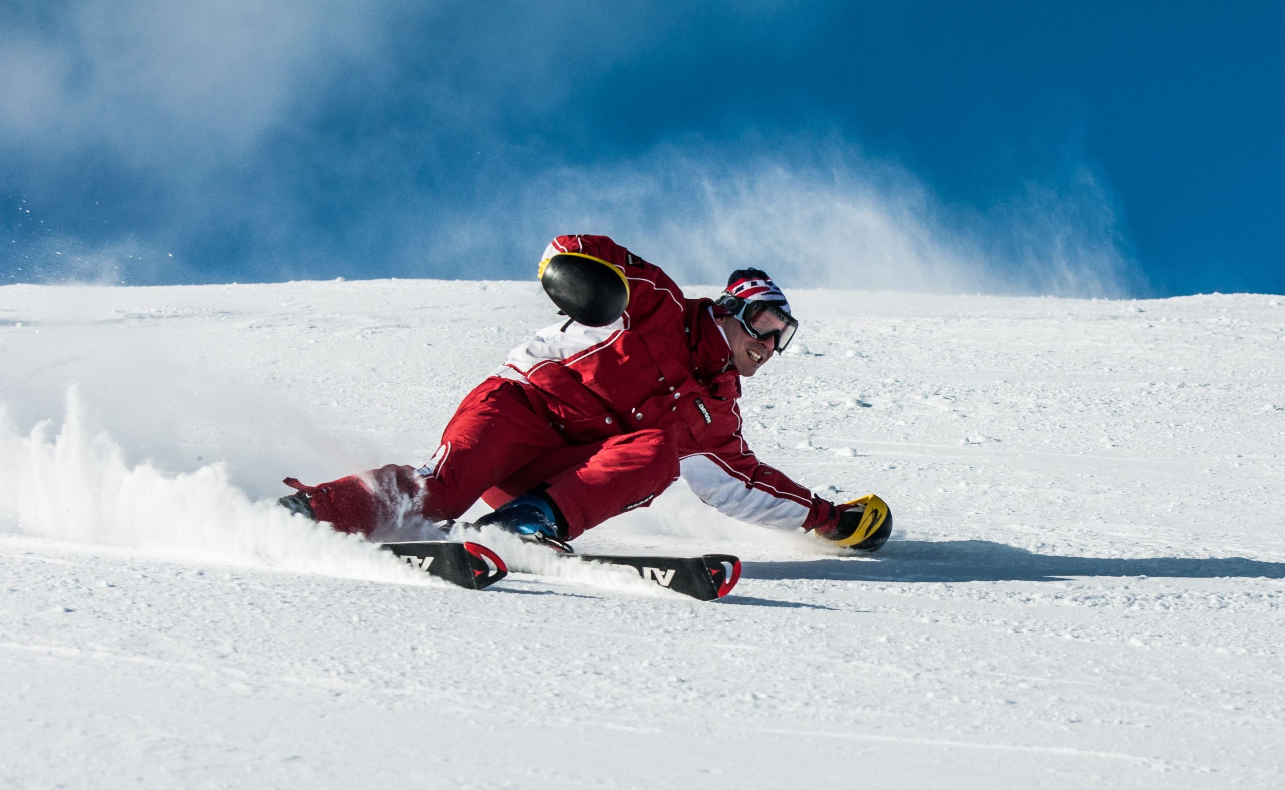 Skieur en rouge dévale pente ensoleillée