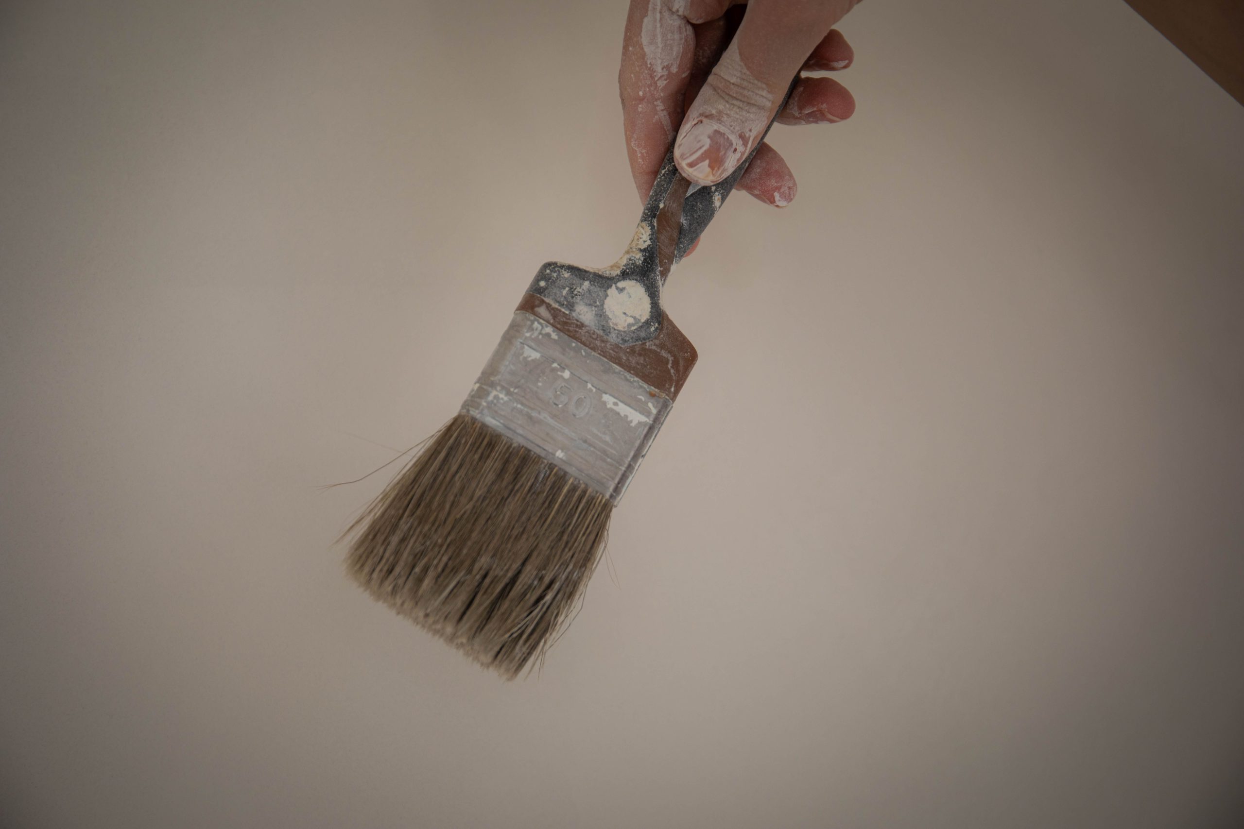 Main tenant un pinceau avec des résidus de peinture