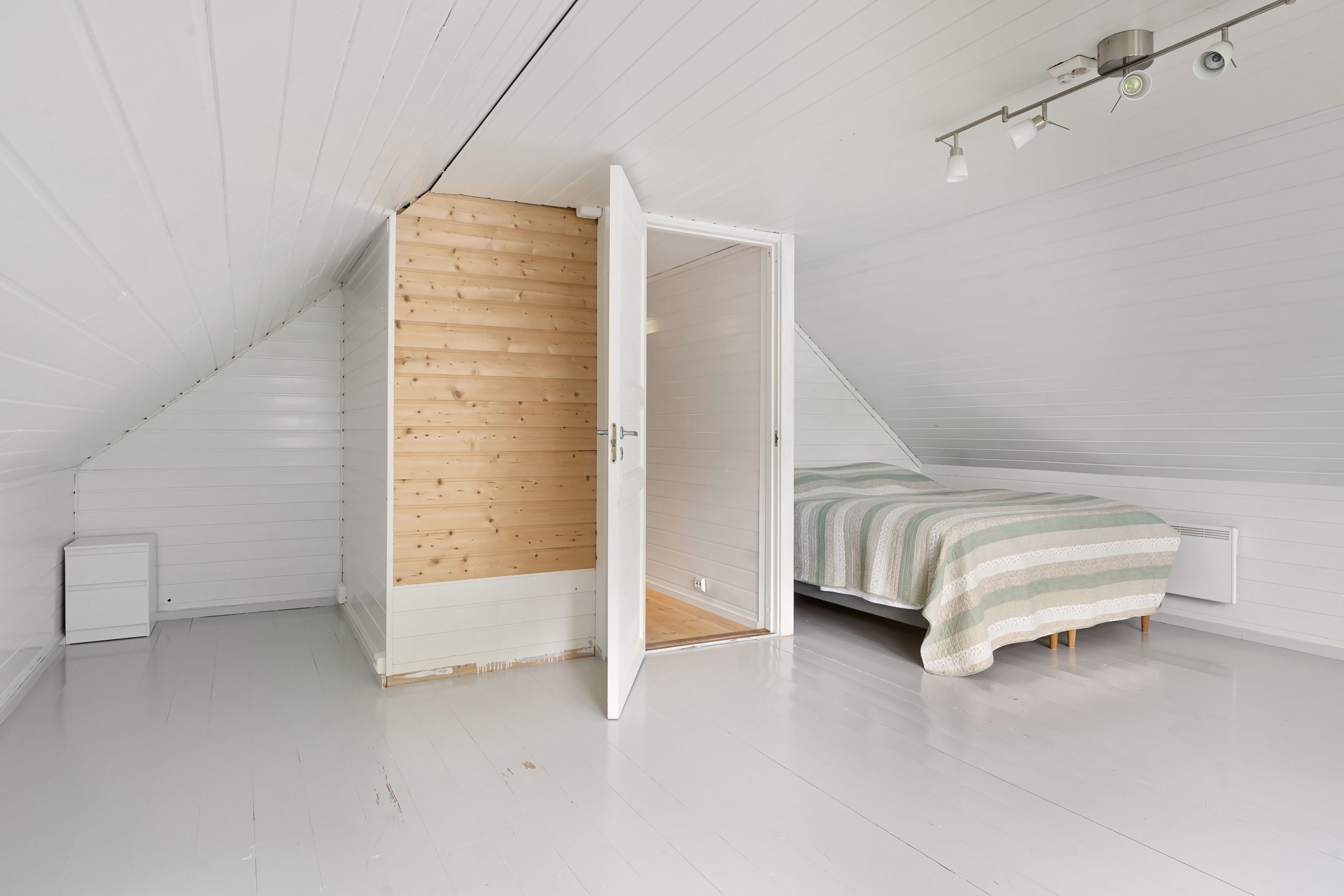 Chambre mansardée moderne aux murs blancs minimaliste