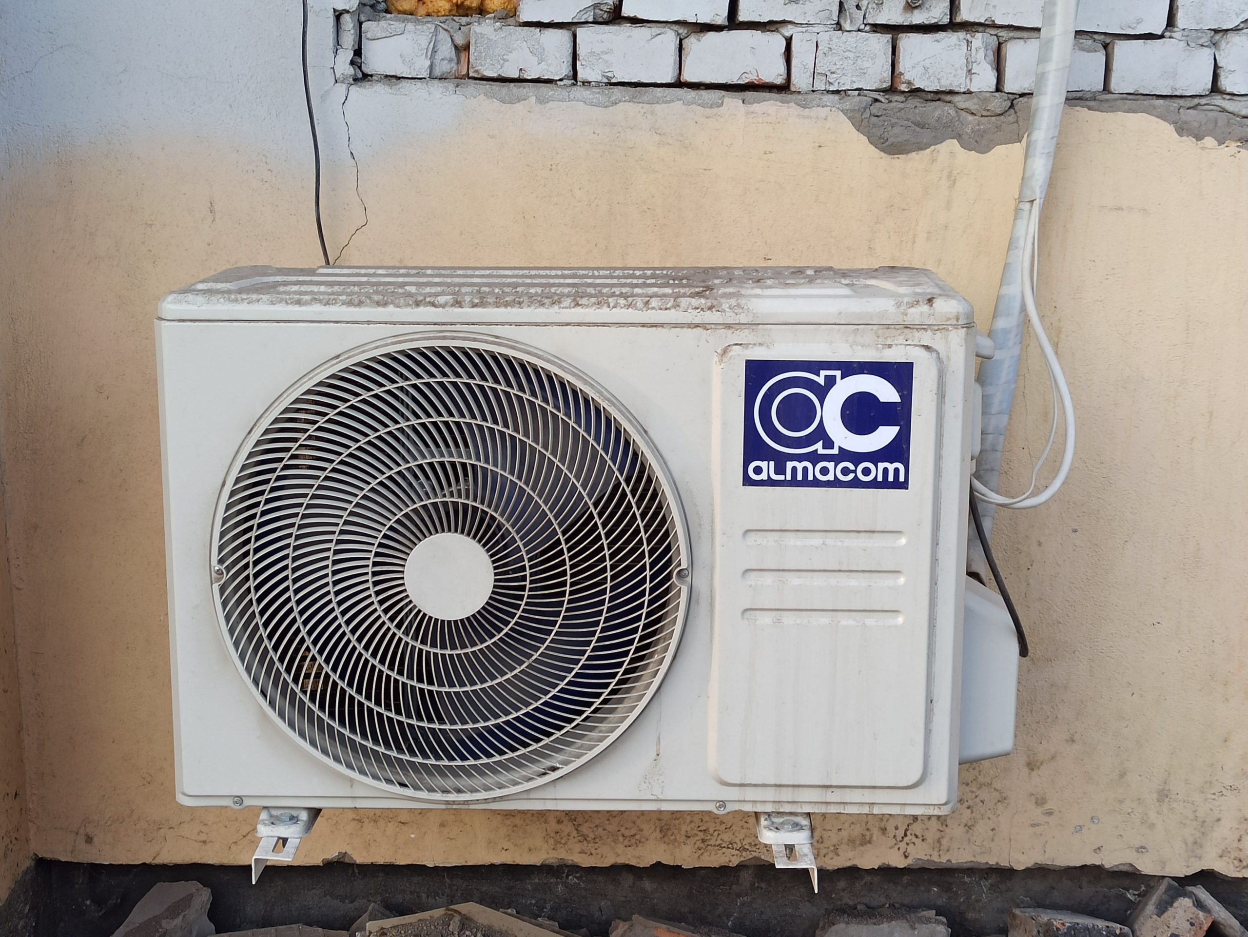 Unité climatisation usagée fixée mur brique
